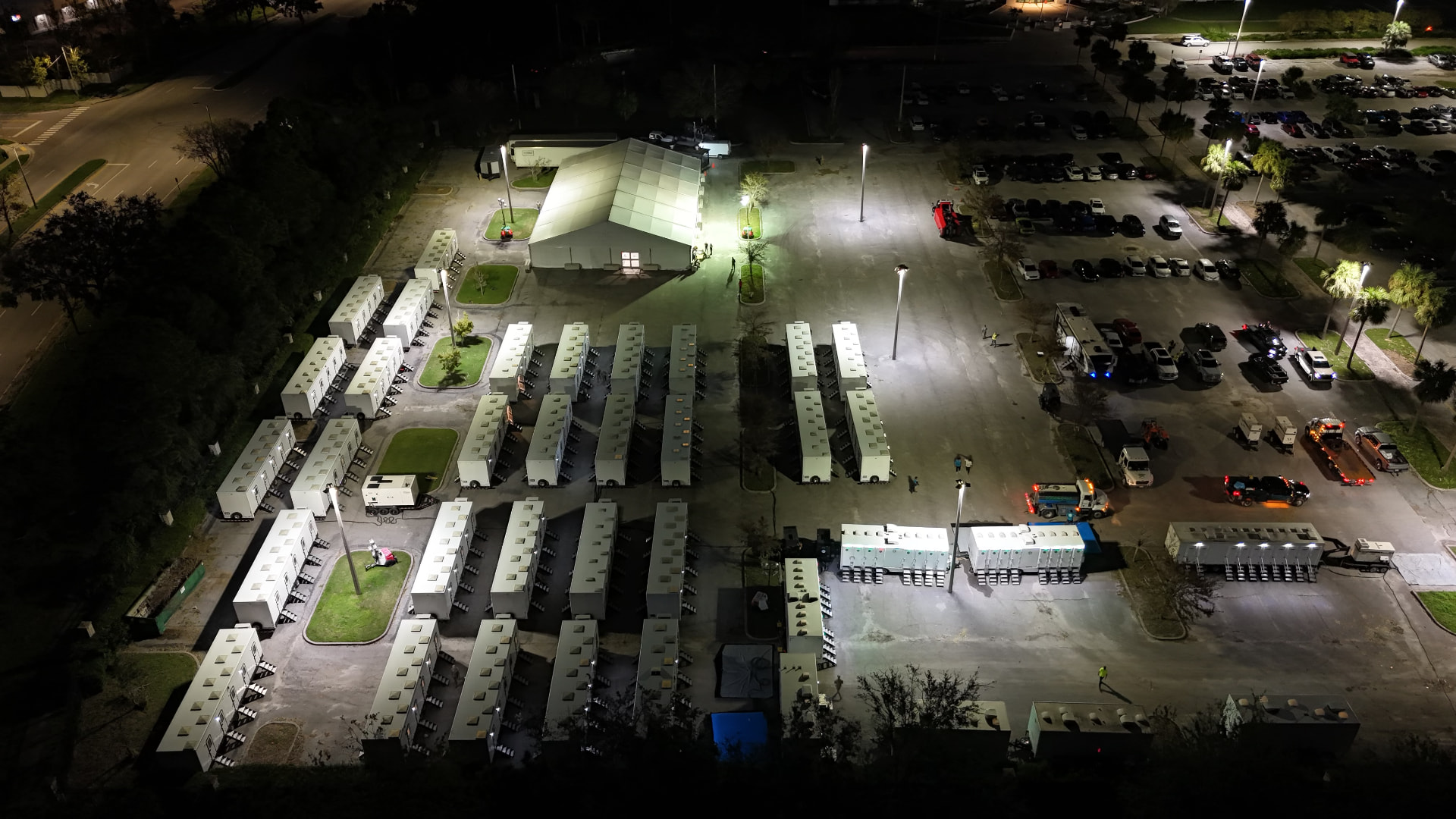 Disaster response base camp staged overnight with lit tents and sleeper trailers